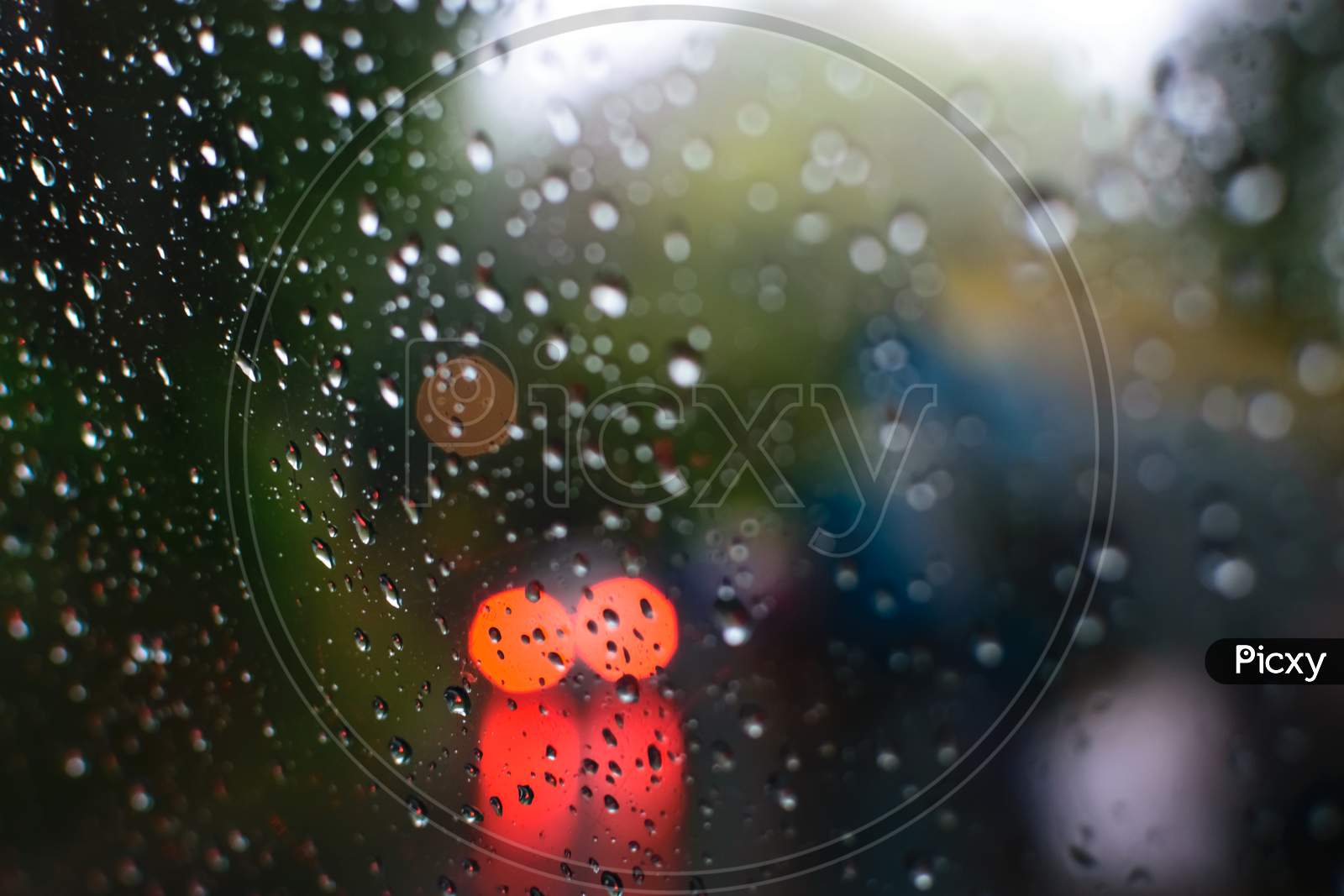 Rain Drops On A Glass With Visible Red Lights Of A Car Through The Glass