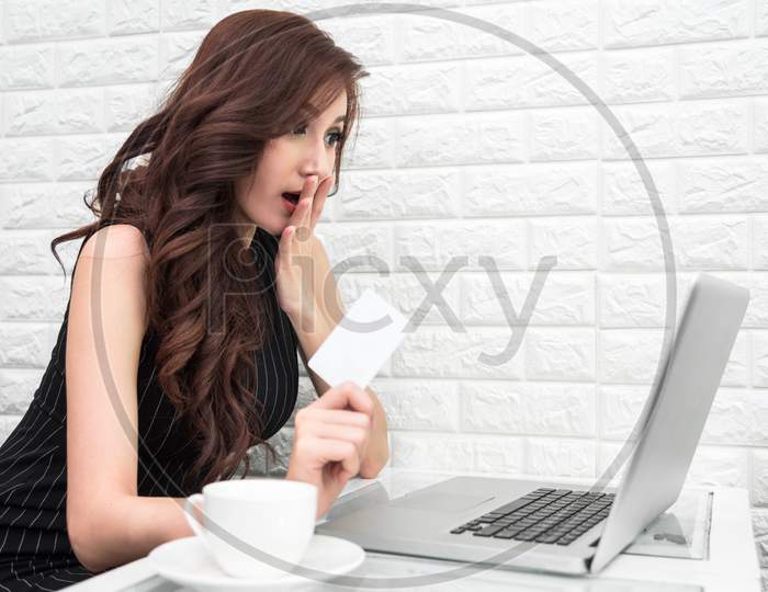 Asian Woman Surprising When Use Credit Card For Online Shopping With Laptop. Business And Banking Payment Concept. Price Sale And Promotion Concept. Technology And Internet Communication Theme.
