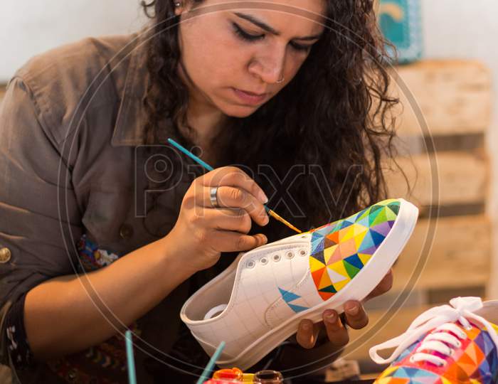 A Female Painter Decorating A Shoe.