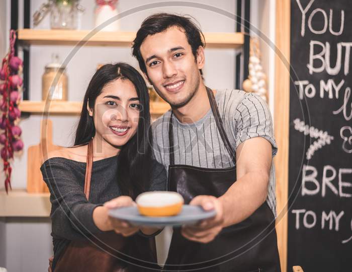 Young Couples Making Bakery Donuts And Bread At Bakery Shop As Business Ownership Entrepreneur. Husband And Wife Cooking Together In Kitchen. Happiness People And Lifestyle Relationship Concept
