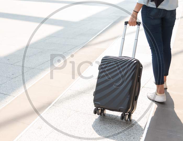 Close Up Woman And Suitcase Trolley Luggage In Airport. People And Lifestyles Concept. Travel And Business Trip Theme. Woman Wear Jeans Going On Tour And Traveling Around The World By Alone Solo Girl