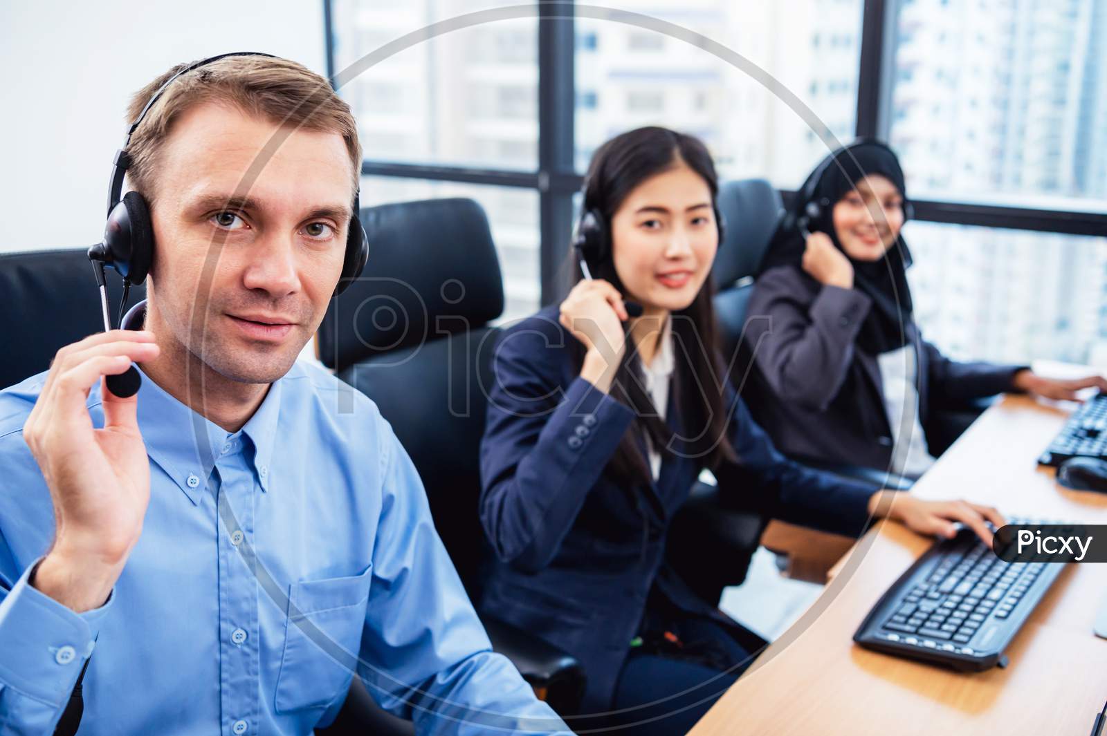 Group Of Young Profession Call Center Operator Agent With Headsets Working In Office. Business Telemarketing Service People Concentrating On Having Conversation Work And Talking To Customer Friendly