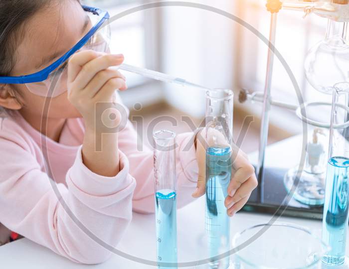Asian Child Chemist Holding Flask And Test Tube In Hands In Lab Learning Chemistry Experiment. Scientist Chemistry And Science Education Concept. Kids Dream Job Occupation