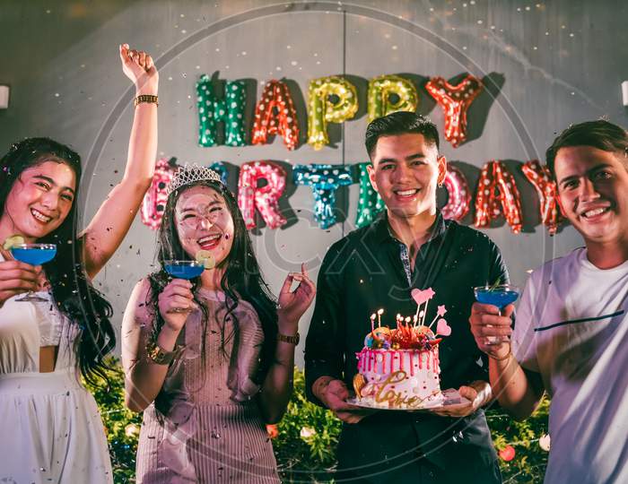 Asian Friends Having Fun In Outdoor Birthday Party At Night Club With Birthday Cake. Event And Anniversary Concept. People Lifestyles And Friendship. Group Of Young Adult Celebrating And Anniversary
