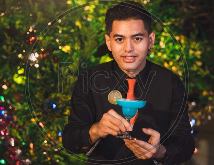 Professional Bartender Preparing Fresh Blue Juice Cocktail In Drinking Wine Glass With Ice At Night Bar Clubbing Counter. Occupation And People Lifestyles Concept. Outdoor And Nightclub Garden