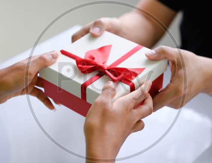 Closeup Of Hands Giving Gift Box In Christmas Day And New Year Festival To Each Other. Holiday And Event. Surprising Giftbox In Dating On End Year Party. People Lifestyle And Object Concept.