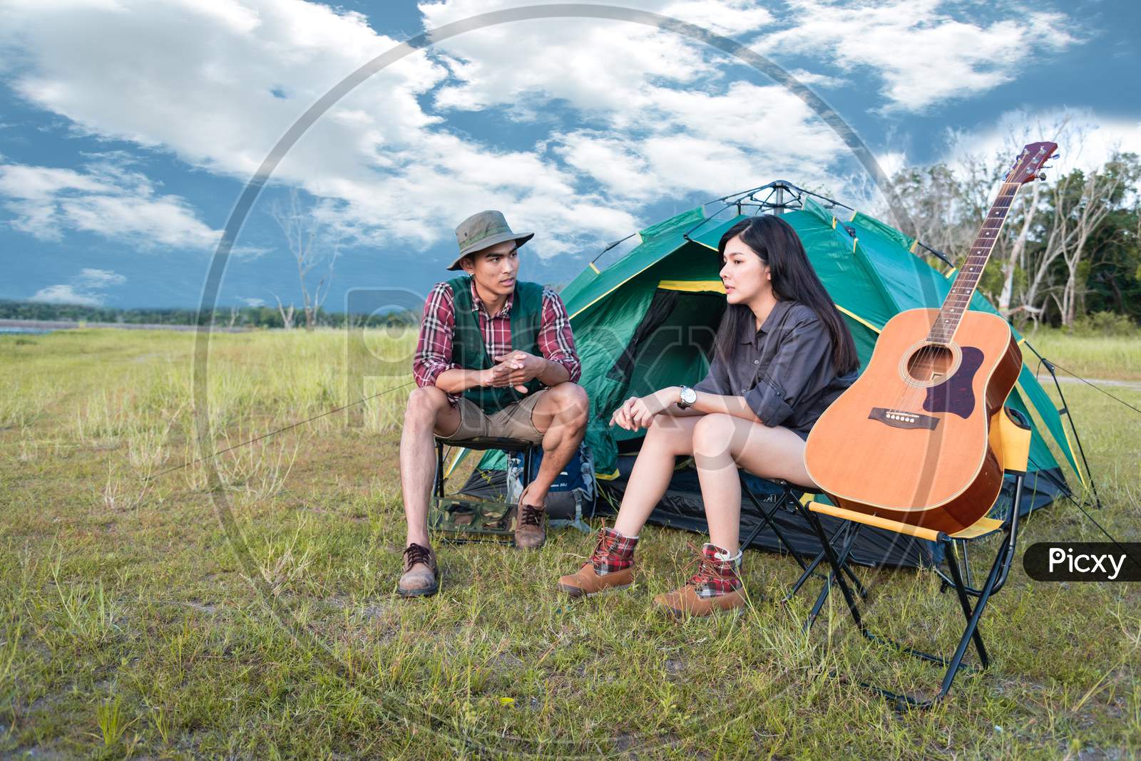 Two People Talking Near Camping Tent In Meadow Field. Male And Female Traveler Looking At Attraction View Point. Couples Adventure At Outdoors Together. People And Lifestyles Concept
