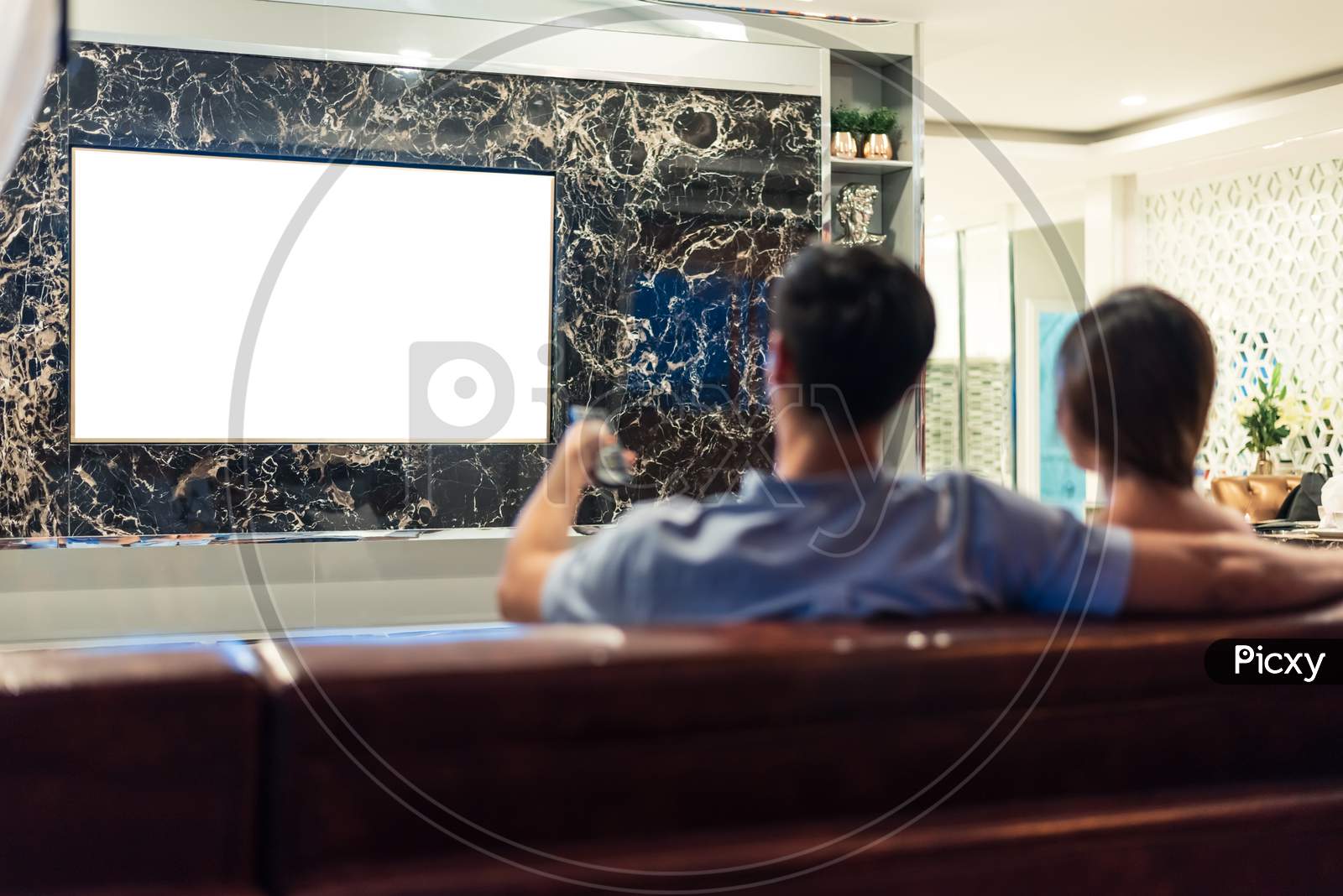 Asian Couples Watching White Blank Screen Display Television For Advertising Template Background.  People Lifestyles Concept. Lockdown Social Distancing Work From Home. Selective Focus On Tv