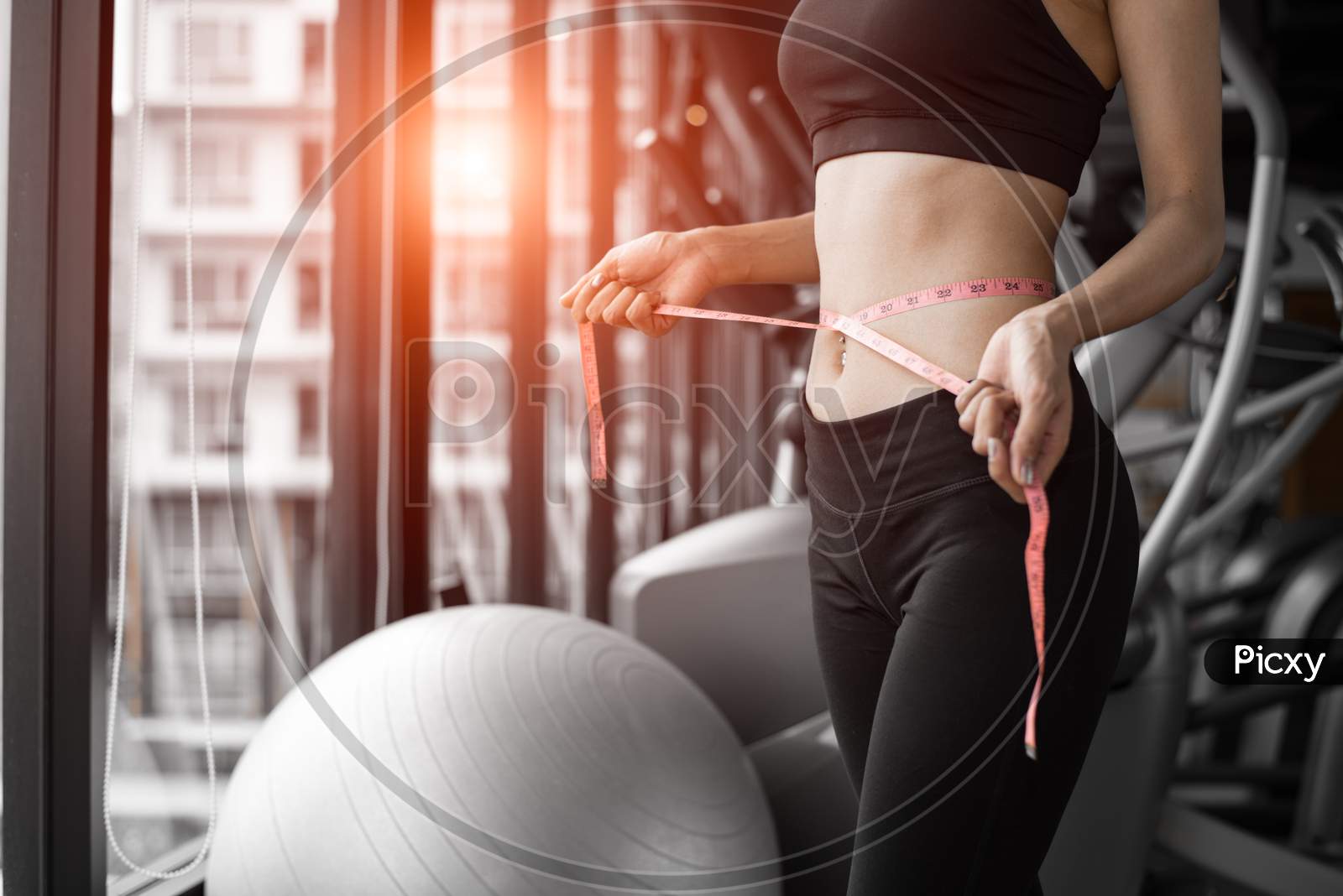 Sporty Woman Using Waist Tape Line In Fitness Gym Sport Club Training Center Near Window With Condominium Background. Lifestyle Of People Workout Exercise Sport Activity. Diet And Weight Loss Theme.