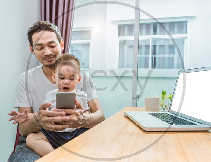 Asian Father And Son Using Smart Phone Together In Home Background. Technology And People Concept. Lifestyles And Happy Family Theme. Internet And Communication Theme