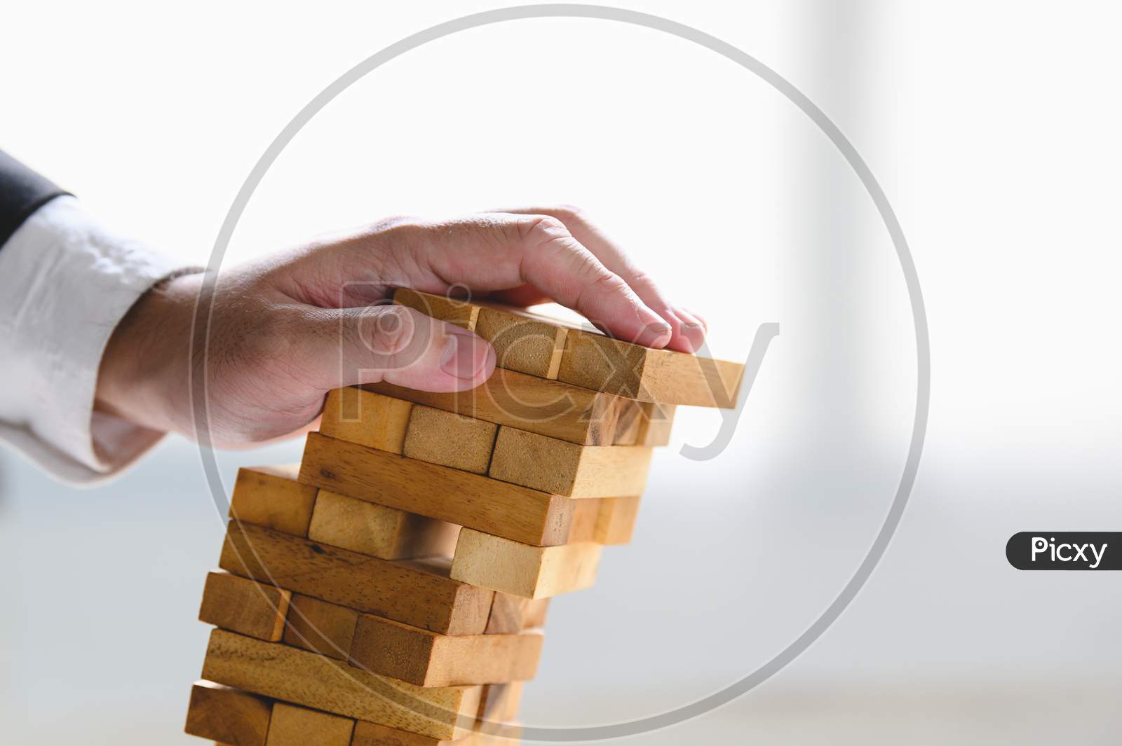 Businessman Collapsing Stacked Tower Wood Block By Hand As Failure Or Bankrupt Project. Business Organization And Company Unsuccessful Progress. Strategy And Money Investment. Risk Management