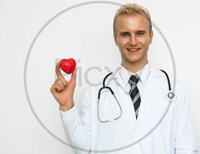 Handsome Male Doctor Holding Red Heart And Smiling. Healthcare And Medical Concept. Happiness People And Lifestyle Theme.