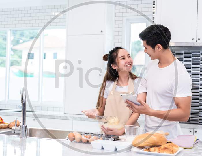 Asian Couples Cooking And Baking Cake Together In Kitchen Room At Home. Love And Happiness Concept Sweet Honeymoon And Valentine Day Theme