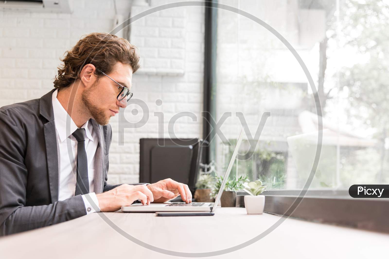 Business Man Working Hard With Laptop On Desk In Office Near Window. Business And Success Concept. People And Occupation Concept. Technology And Computer Theme. Indoors And Interior Theme