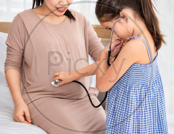 Cute Daughter Listening To Voice Or Heart Beat Of Baby In Mother Belly For Checking New Life. Pregnant And Parent. Health And Medical. People Lifestyle And Family Concept. Motherhood And Sister Relate