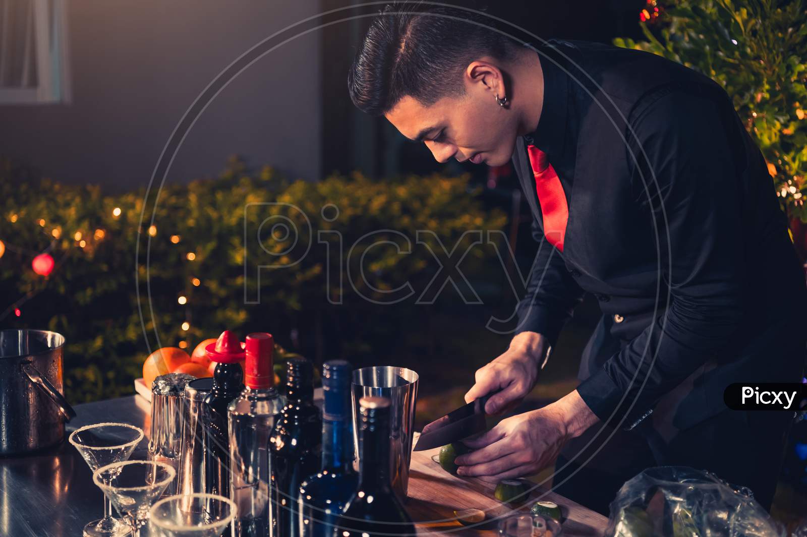 Professional Bartender Preparing Fresh Lime Lemonade Cocktail In Drinking Wine Glass With Ice At Night Bar Clubbing Counter. Occupation And People Lifestyles Concept. Outdoor Background