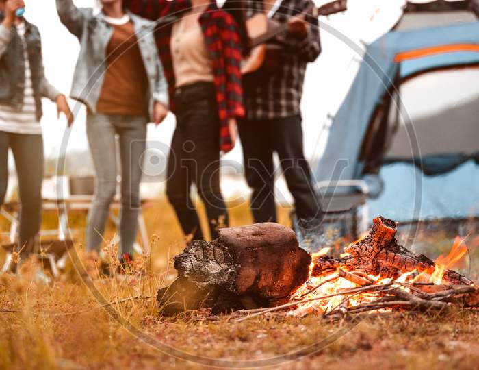 Closeup Of Campfire And Friendship Dancing To Beat Of The Music For Celebrating In Party With Mountain Meadow And Lake View Background. People Lifestyle And Travel Vacation. Picnic And Camping Tent