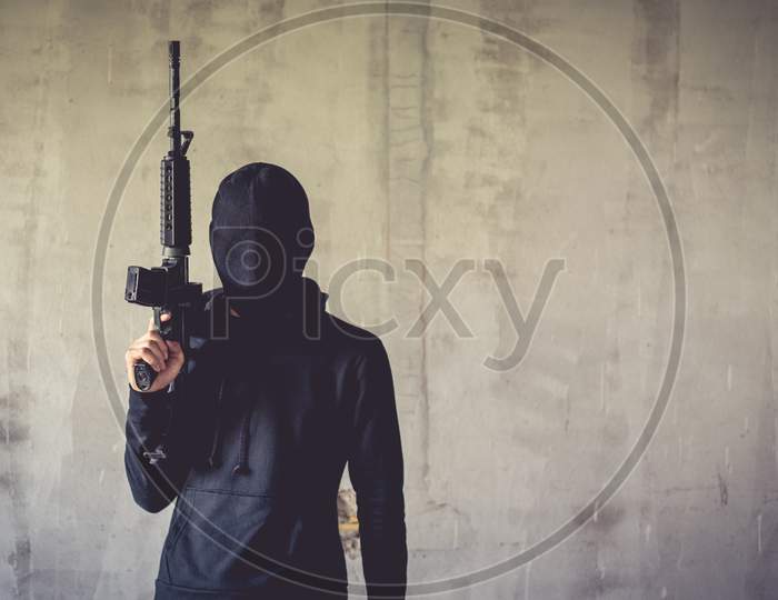 Terrorist Holding Rifle Gun On Grunge Wall. Social Issued Theme. Terrorist And Robber Concept. Police And Soldier Theme. Social Issued Theme.