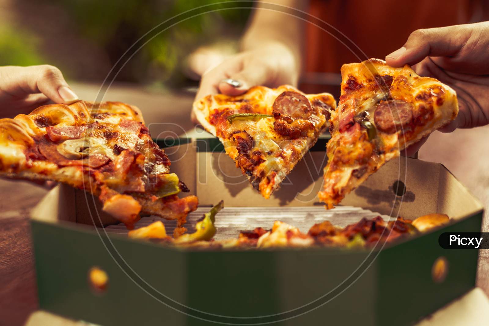 Close Up Of Sliced Hot Pizza Holding By Friendship People Hands For Celebration Party. Pizza Margarita Cuisine With Cheese And Sausage On Crispy Pan Delivery Service. Delicious And Tasty Italian Food