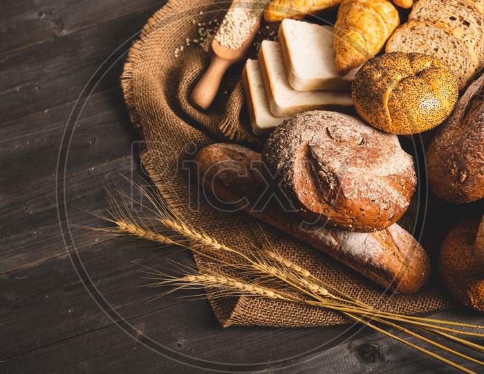 Different Kinds Of Bread With Nutrition Whole Grains On Wooden Background. Food And Bakery In Kitchen Concept. Delicious Breakfast Gouemet And Meal. Top View Angle