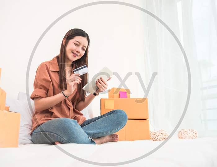 Young Asian Woman Startup Small Business Entrepreneur Sme Distribution Warehouse With Parcel Mail Box. Owner Home Office. Online Marketing And Product Packaging And Delivery Service. Credit Card Use