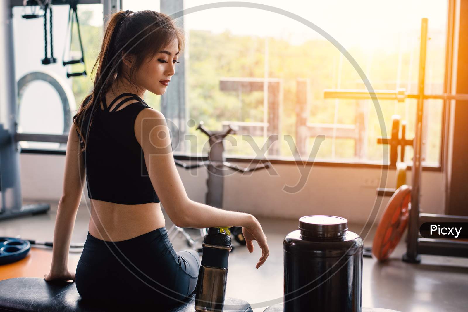 Foto Stock Athletic girl with shaker in gym. Fitness woman drinking water  from a bottle