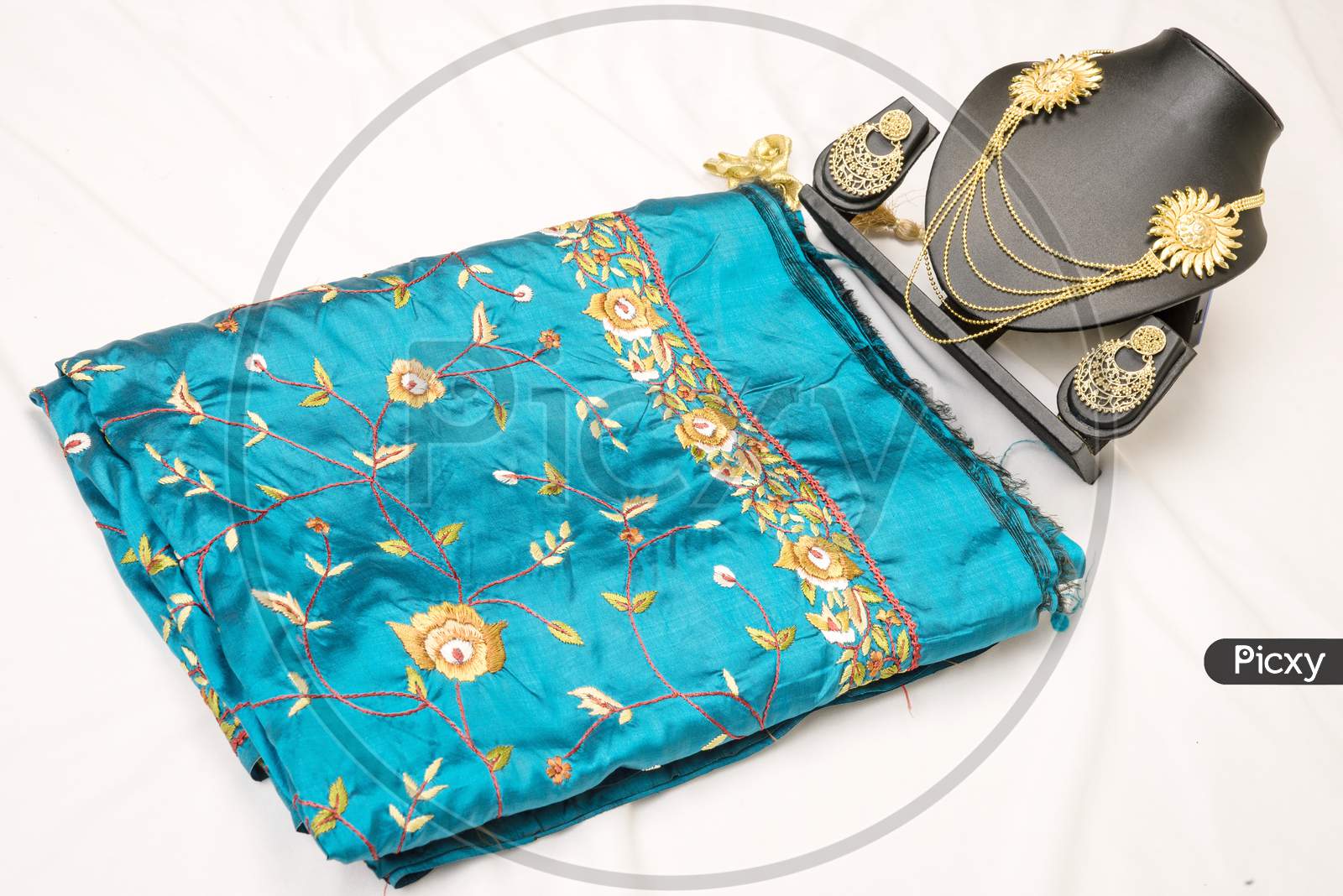 Folded blue colour fabric  placed on a white  background kept with Indian Jewelries