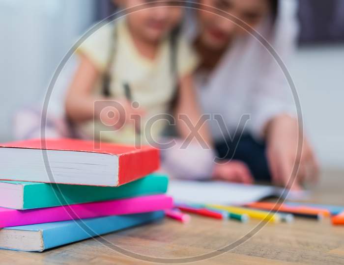 Close Up Of Books On Floor With Mom And Kids Background. Back To School And Education Concept. Children And Teacher Theme.