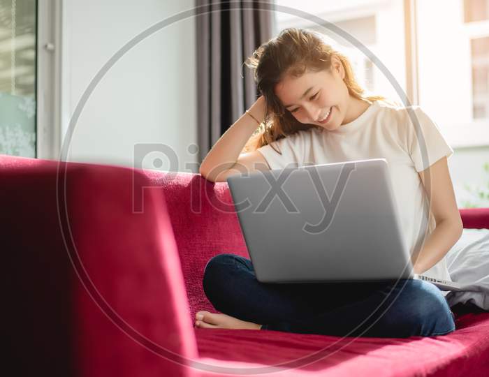 Young Woman Shopping Online With Internet In Happy Mood On Red Sofa. Business And Working Concept, Relax And Part Time Concept