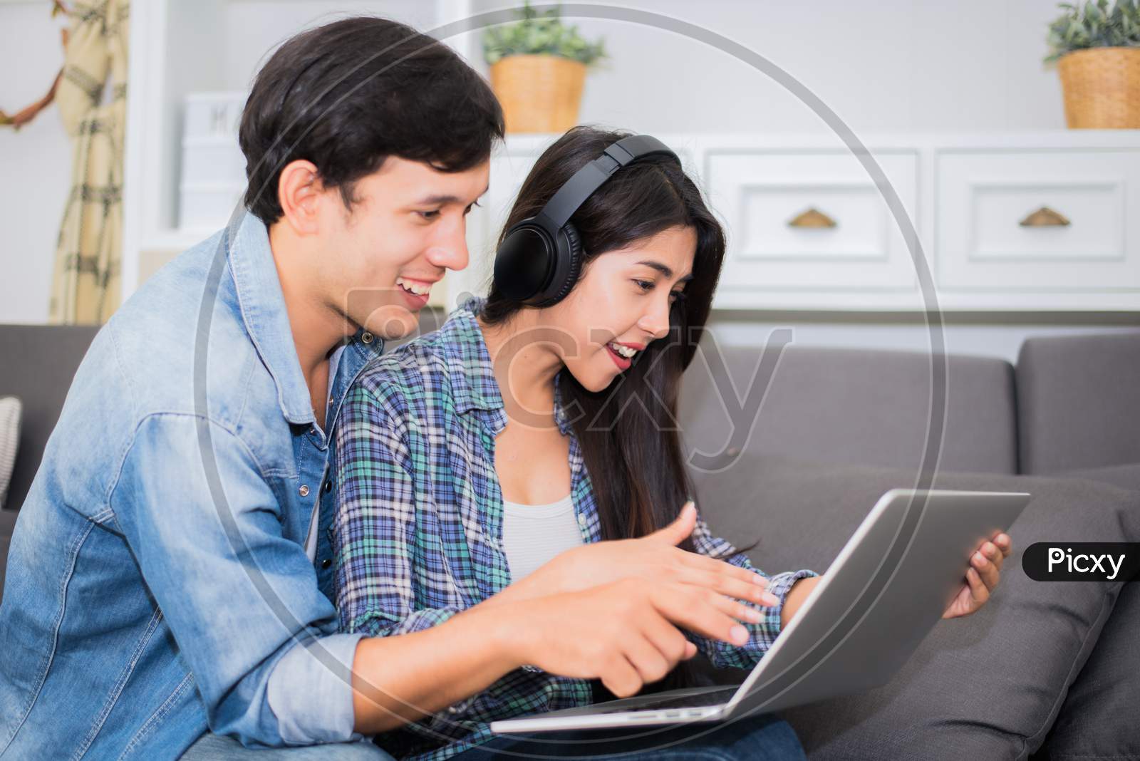Lovers Or Couple Using Laptop And Listening Music With Headphone In House. Honeymoon And Entertainment Concept. Happiness And Lifestyle Concept. Communication Technology And People In Sweet Home Theme