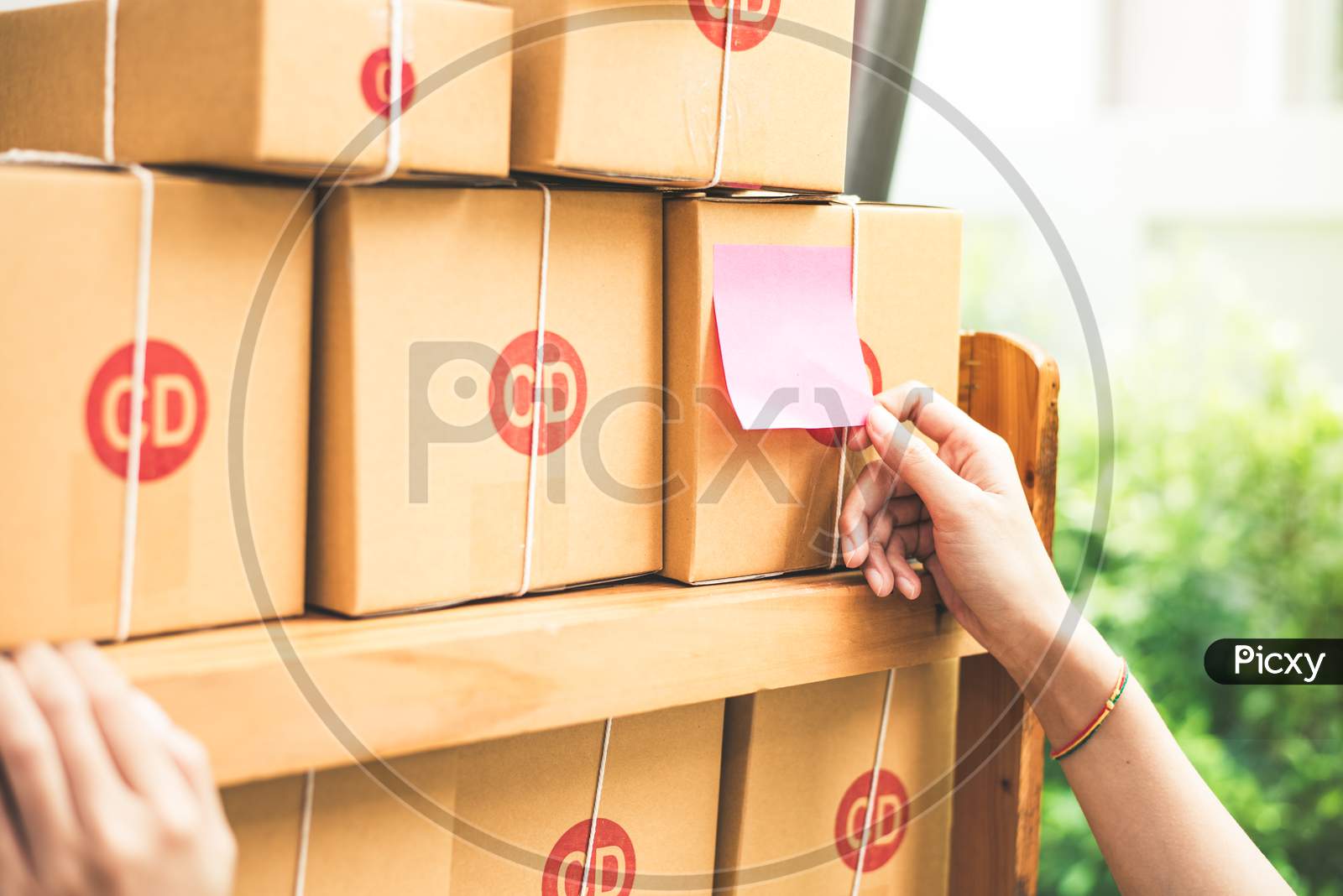 Close Up Of Woman Hand When Sticking Memo Paper To Post Or Parcel Mail Box. Business And Online Shopping Concept. Post Office Delivery And Home Service Order Theme.