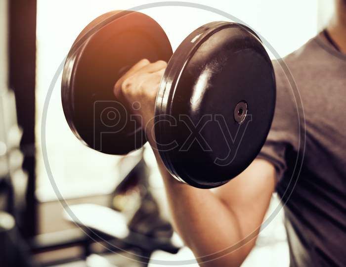 Closeup Of Dumbbell. Young Man Lifting Heavy Weights. Sport Equipment And Workout Concept. Body Builder And Strength Concept. Training Center And Fitness Gym Theme.