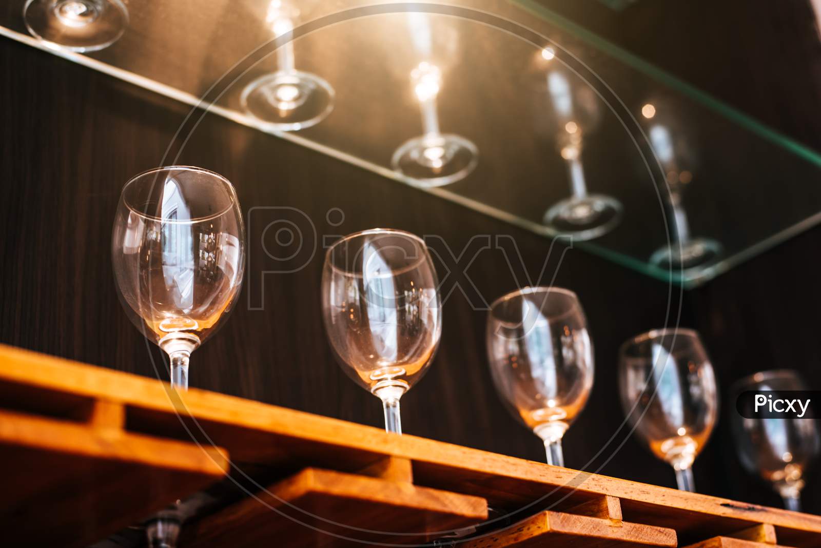 Drinking Wine Glasses Shelf In Restaurant With Lighting Showcase Background. Many Clean Containers In Restaurant Or Night Pub And Bar. Interior Decoration And Beverage Party Concept.