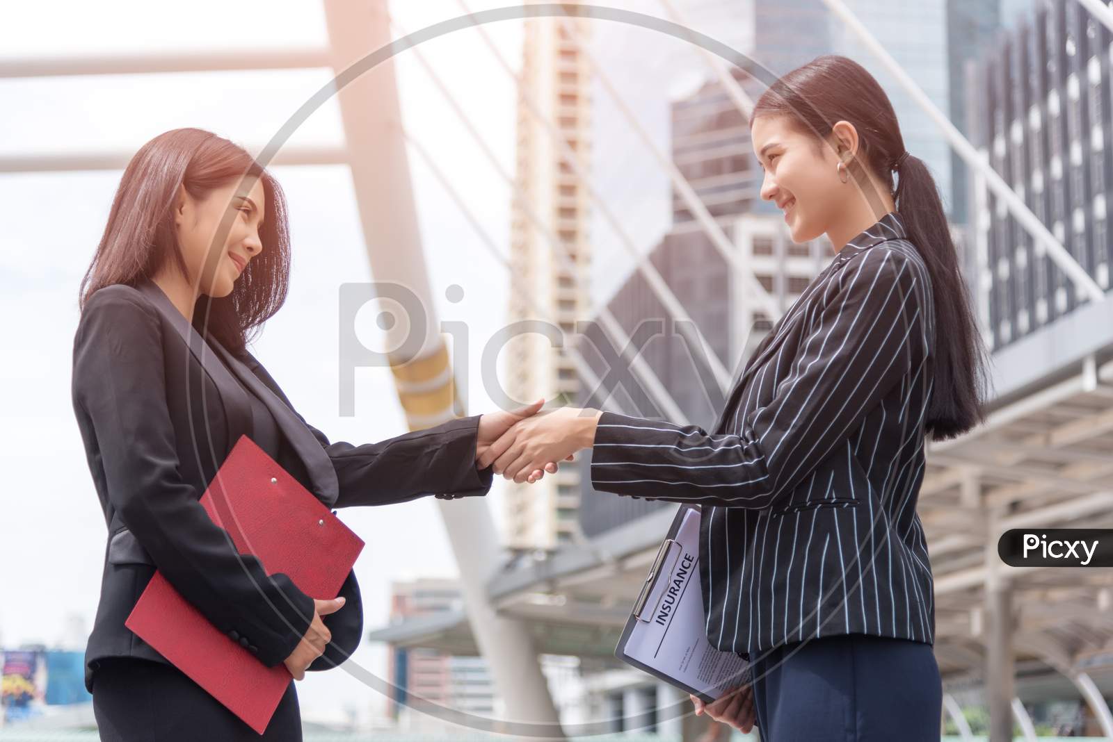 Two Business Women Hand Shake At Outdoors With Traffic Background, Business And Contact Agreement Concept