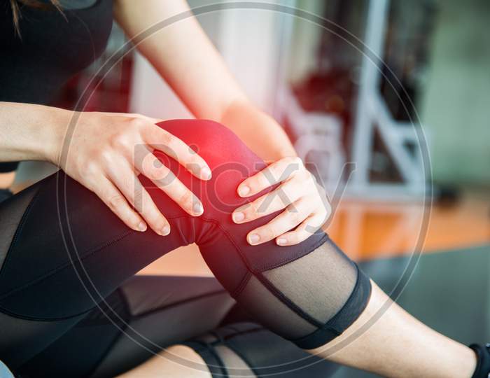 Sports Injury At Knee In Fitness Training Gym. Training And Medical Concept. Health Care And Sport Exercise Concept. Pain Of Body Part And Bone Broken Theme. First Aid And Safety First Theme