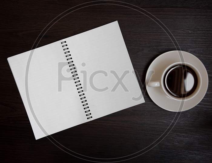 Top View Of Coffee Cup And Blank Notebook For Memo On Wooden Background. Business And Object Concept. Memo And Reminder Theme.