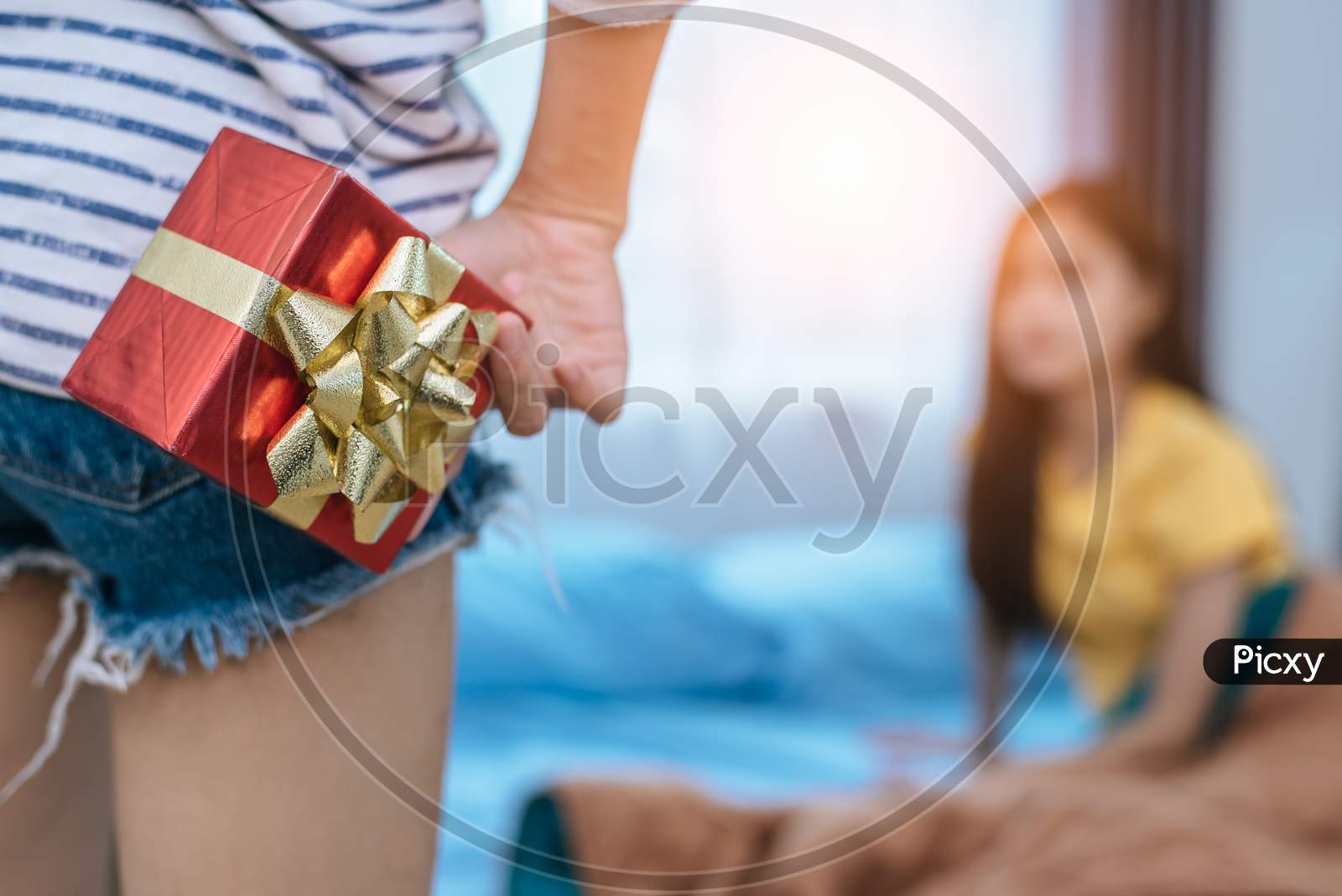 Close Up Of Woman Hands Holding Gift For Surprise Her Girlfriend In Bedroom. Person And People Concept. Lifestyles And Happiness Life Concept. Lesbian And Homosexual Theme.