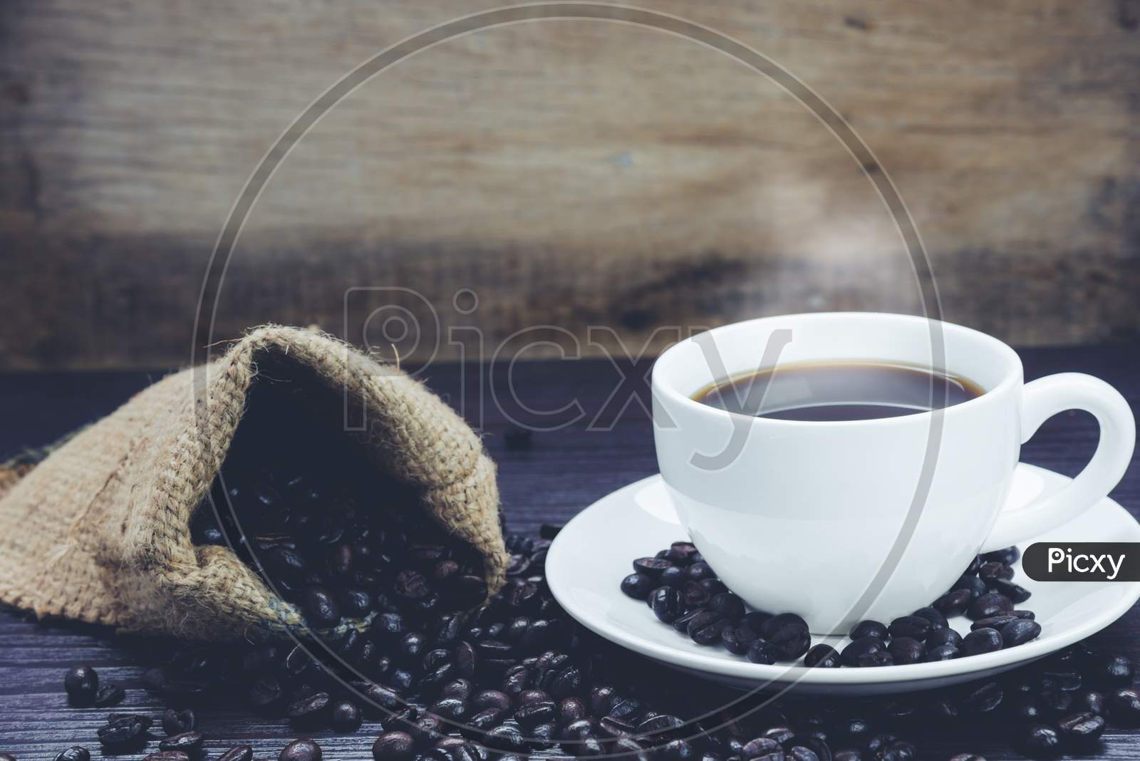 Side View Of Coffee Cup With  Smoke And Coffee Beans In Sack On Wood Table, Drinks And Relax Concept, For Advertising