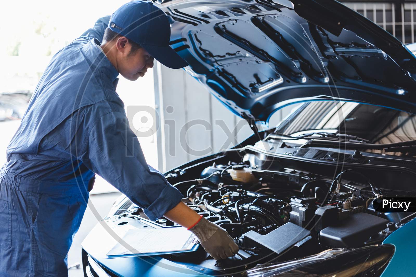 Car Mechanic Checking To Maintenance Vehicle By Customer Claim Order In Auto Repair Shop Garage By List In Clipboard. Engine Repair Service. People Occupation And Business Job. Automobile Technician