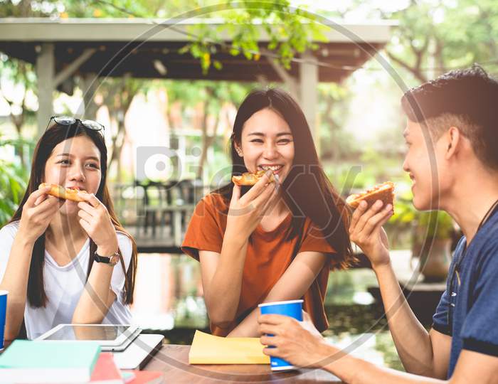 Young Asian People Eating Pizza Together By Hands. Food And Friendship Celebration Party Concept. Lifestyles And People In Theme. Happiness Of Enjoy Life Of College People During Tutoring In Classroom