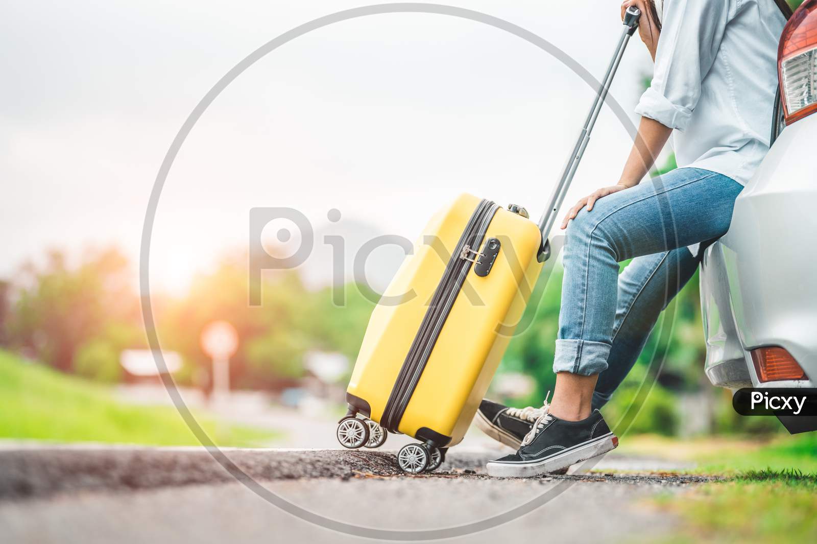 Closeup Lower Body Of Woman Leg Relaxing On Car Trunk With Trolly Luggage Along Road Trip With Autumn Mountain Hill Background. Freedom Road Way. People Lifestyle Transportation Travel In Vacation