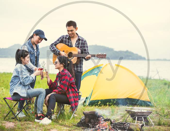 Group Of Asian Friendship Clinking Drinking Bottle Glass For Celebrating In Private Party With Mountain And Lake View Background. People Lifestyle Travel On Vacation Concept. Picnic And Camping Tent