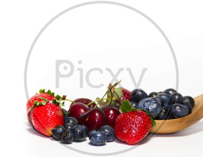 Red Fruits On White Background And Wooden Spoon