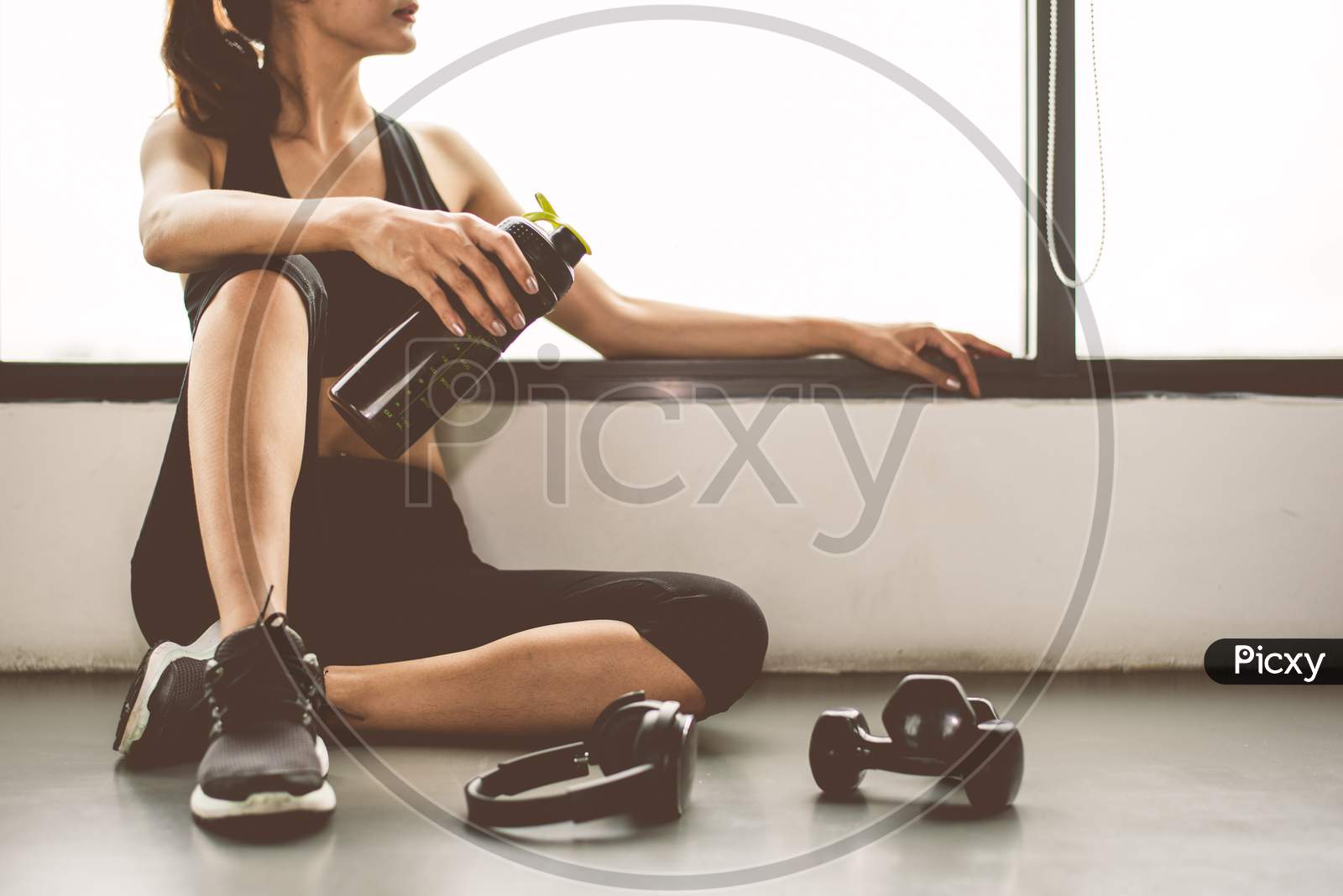 Woman With Dumbbell And Device Exercise Lifestyle Workout In Gym Fitness Breaking Relax After Sport Training With Protein Shake Bottle Background. Healthy Lifestyle Bodybuilding And Athlete Muscles