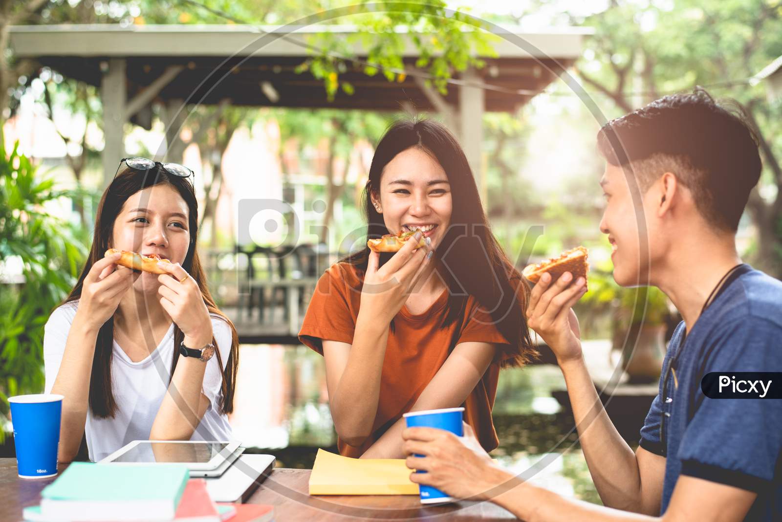 Young Asian People Eating Pizza Together By Hands. Food And Friendship Celebration Party Concept. Lifestyles And People In Theme. Happiness Of Enjoy Life Of College People During Tutoring In Classroom