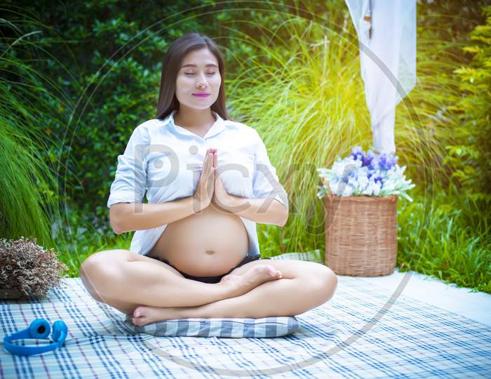 Pregnant Woman Doing Yoga At The Outdoor