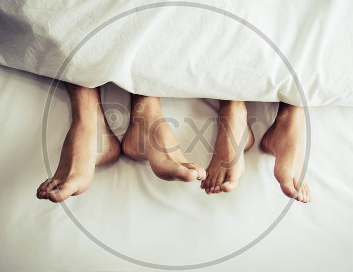 Barefoot Of Lovers Under Blanket In Bedroom. Vacation And Happiness Of Sexual. Valentines Day Theme. Holiday Morning Theme