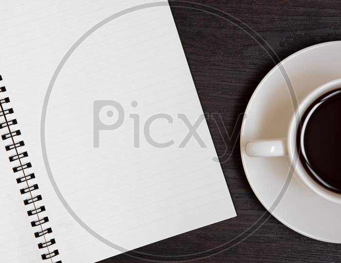 Top View Of Coffee Cup And Blank Notebook For Memo On Wooden Background. Business And Object Concept. Memo And Reminder Theme.