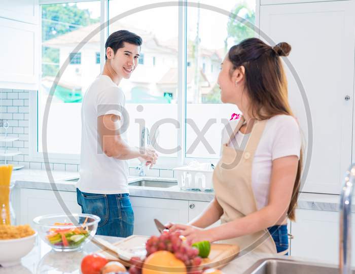 Asian Lovers Or Couples Looking Each Other When Cooking So Funny Together In Kitchen With Full Of Ingredient On Table. Honeymoon And Happiness Concept. Valentines Day And Sweet Home Concept
