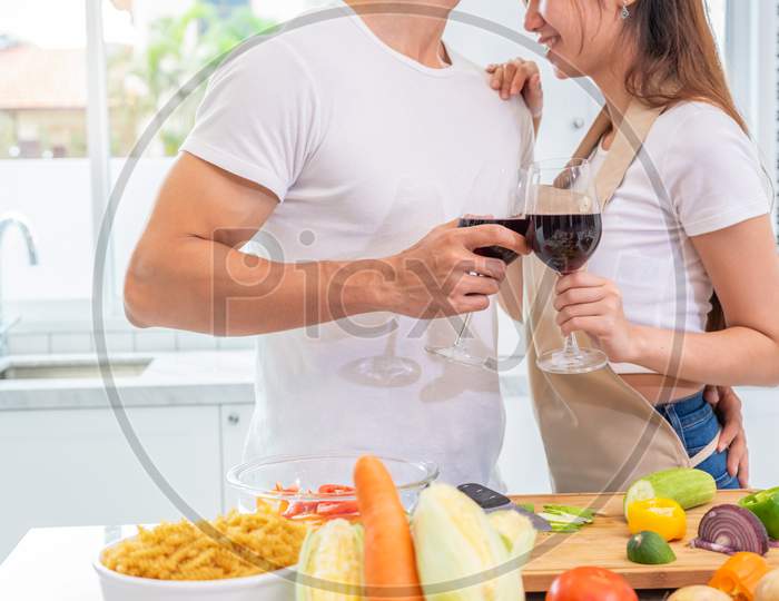 Closeup Of Drinking Wine On Happy Asian Young Married Couple Hands In Home Kitchen. Boyfriend And Girlfriend Cooking Together. People Lifestyle And Romantic Relationship Concept. Valentines Day